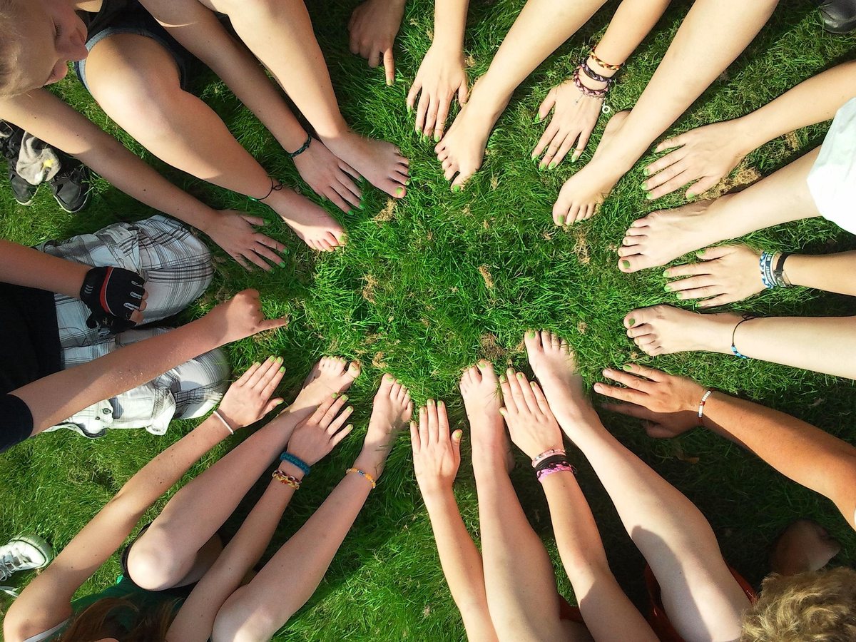 Viele Hände im Kreis auf einer Wiese
