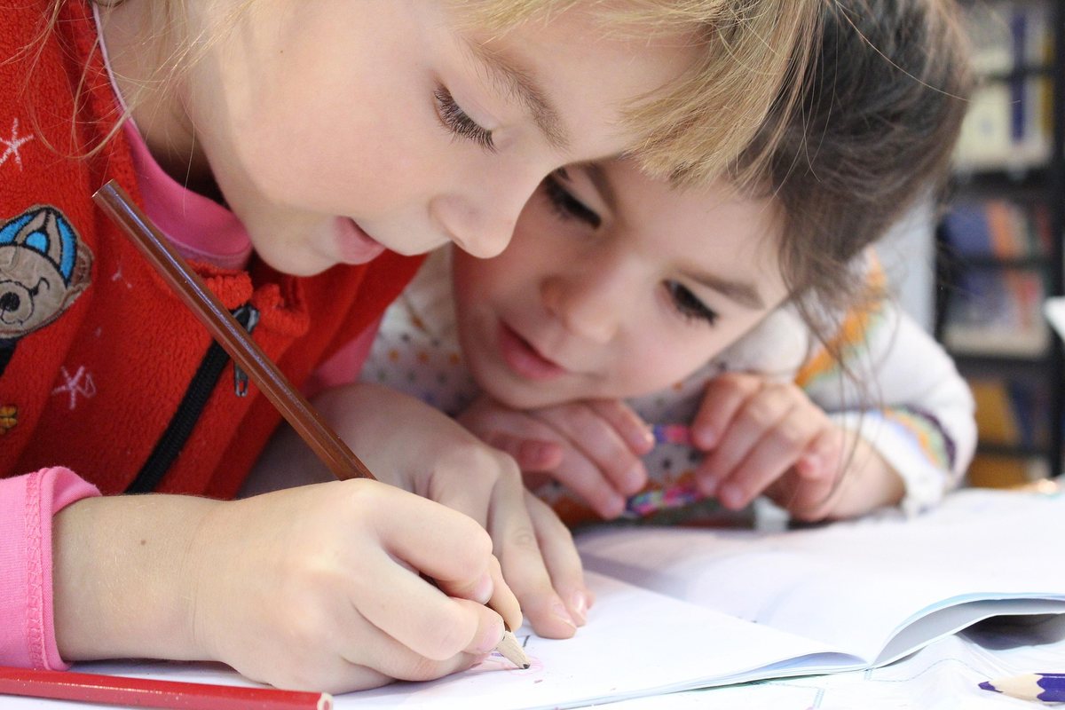 Zwei Kinder schreiben konzentriert in ihre Hefte